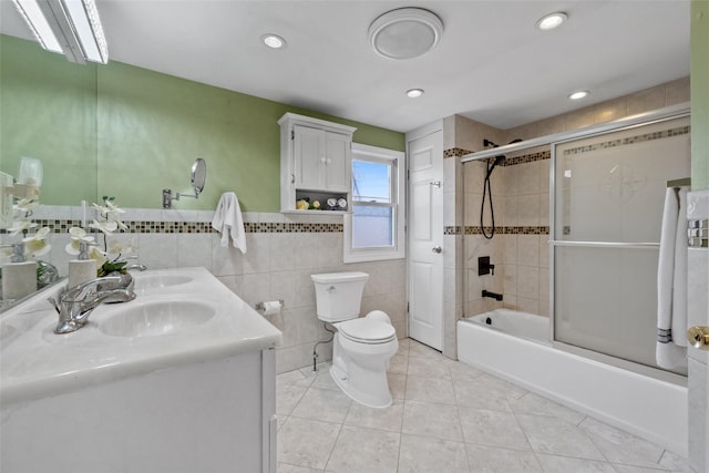 full bath featuring toilet, a sink, combined bath / shower with glass door, tile walls, and tile patterned floors
