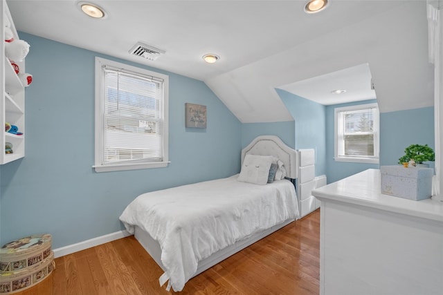bedroom with visible vents, baseboards, wood finished floors, and lofted ceiling