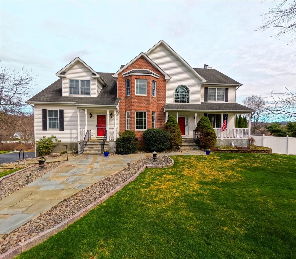 view of front of home featuring a porch, fence, and a front lawn