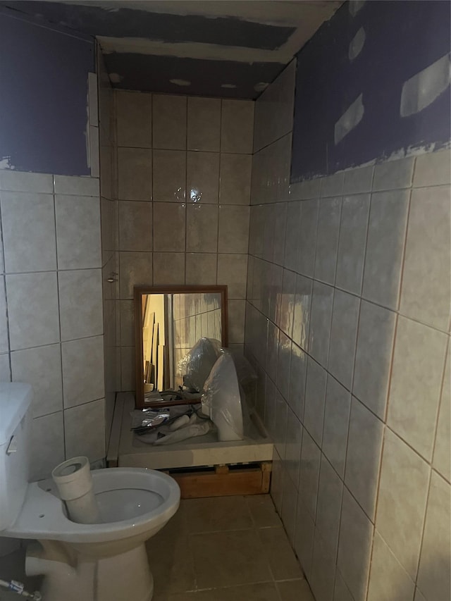 bathroom featuring tile walls, tile patterned floors, and toilet