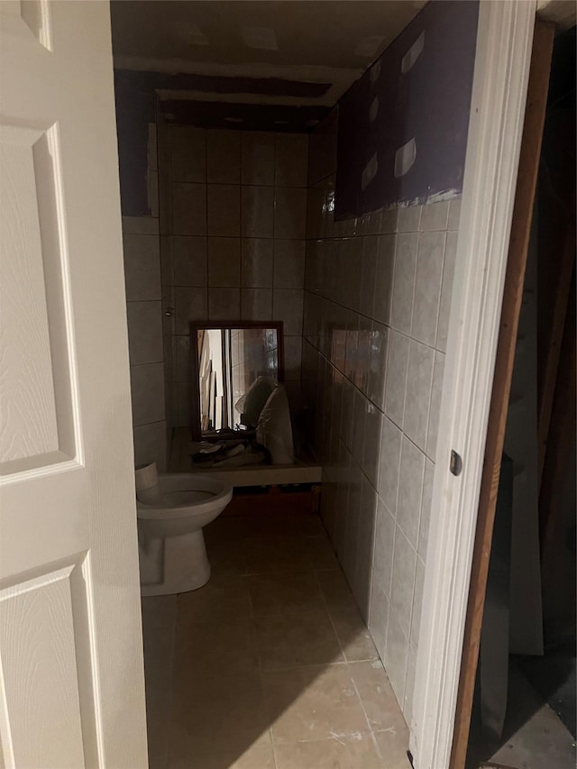 bathroom with tile walls, toilet, and tile patterned flooring