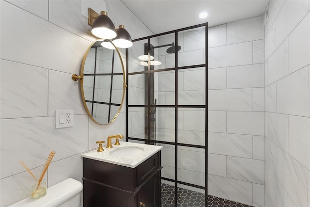 bathroom with tile walls, vanity, a walk in shower, and toilet