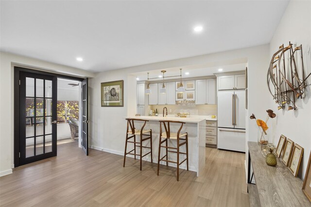 kitchen featuring light wood finished floors, high end white fridge, recessed lighting, and a breakfast bar area