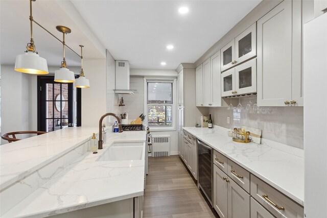 kitchen with wine cooler, a sink, radiator, white microwave, and light wood-style floors