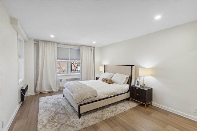 bedroom featuring baseboards, recessed lighting, radiator heating unit, heating unit, and wood finished floors