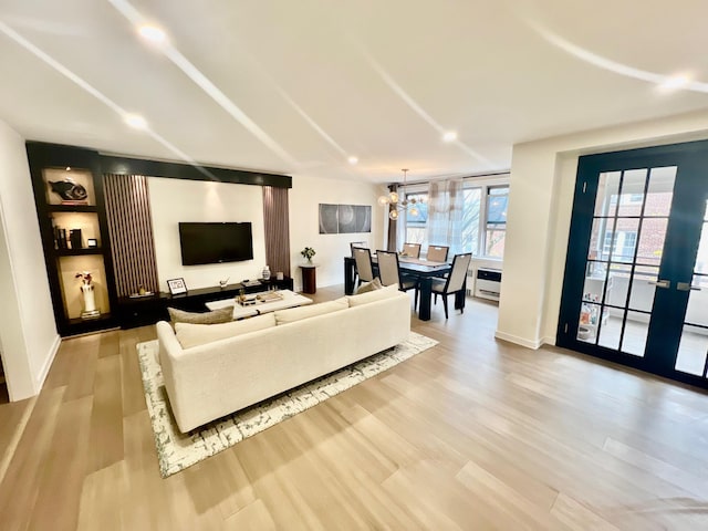 living area with light wood finished floors, heating unit, baseboards, and a chandelier