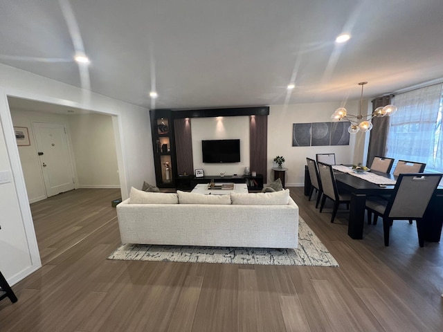 living area with baseboards, wood finished floors, and a chandelier