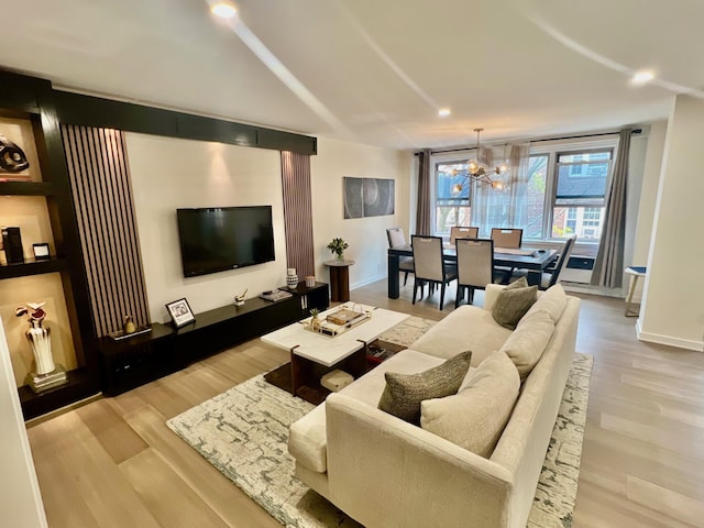 living room featuring baseboards, a notable chandelier, and light wood-style flooring