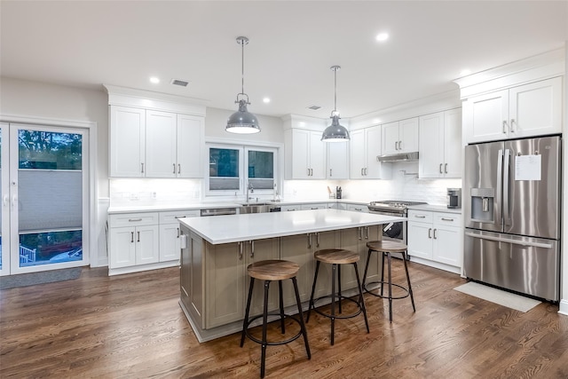 kitchen with white cabinetry, stainless steel appliances, under cabinet range hood, a sink, and a kitchen island