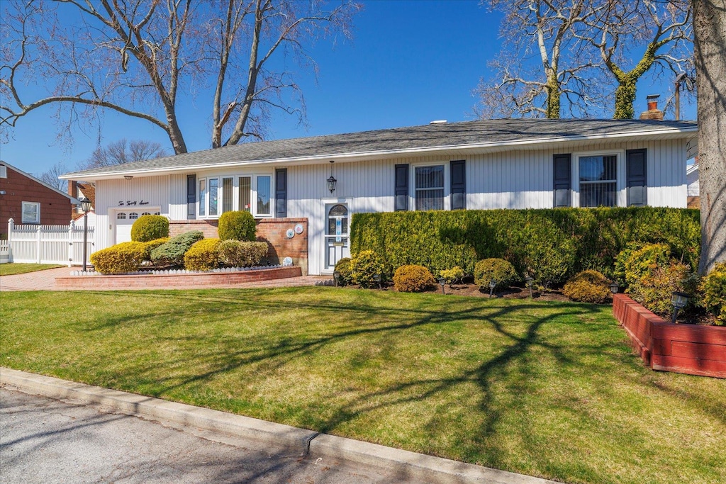 1027 Elizabeth St, Baldwin Harbor, NY 11510 - view of front facade with a chimney, a garage, a front lawn, and fence