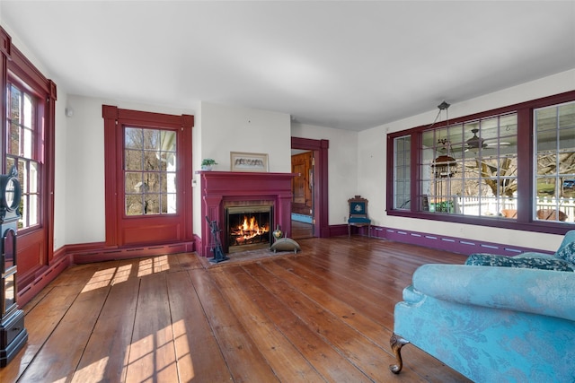 living room with wood-type flooring and a warm lit fireplace