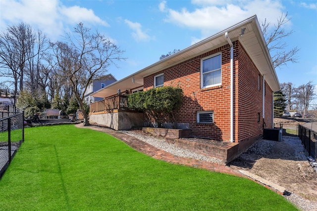 exterior space with brick siding, fence, and a yard