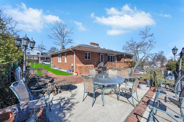 view of patio with fence, a fire pit, a wooden deck, and outdoor dining space