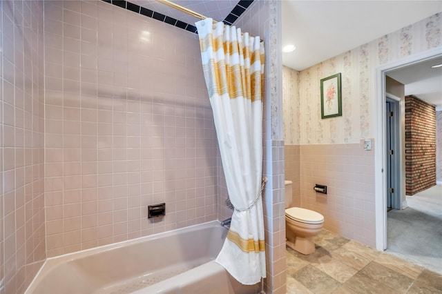 full bath featuring tile walls, wallpapered walls, toilet, shower / bath combination with curtain, and wainscoting