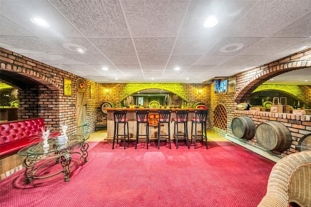 bar featuring a bar, brick wall, and a paneled ceiling