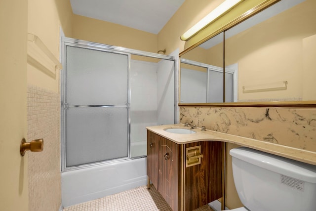 bathroom with tasteful backsplash, vanity, tile patterned flooring, toilet, and bath / shower combo with glass door