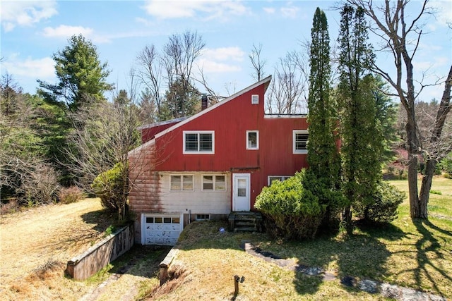 exterior space with a garage, dirt driveway, a lawn, a chimney, and entry steps
