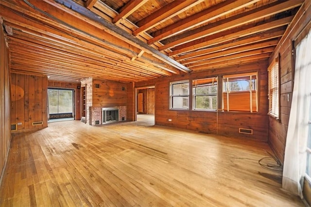 unfurnished living room with wooden walls, hardwood / wood-style flooring, and plenty of natural light