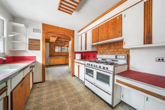 kitchen with visible vents, dark floors, tasteful backsplash, a sink, and double oven range