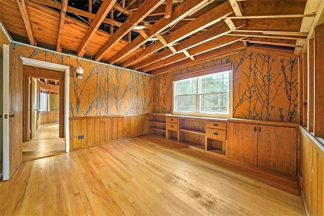 interior space featuring light wood-style flooring, a wainscoted wall, wood walls, and a wealth of natural light