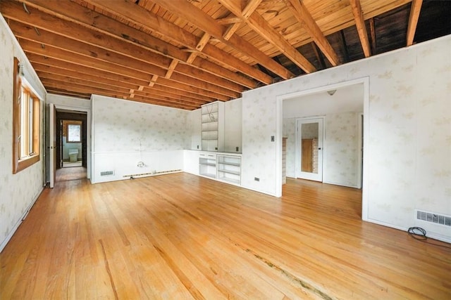 unfurnished living room with visible vents, wallpapered walls, wood-type flooring, and wooden ceiling