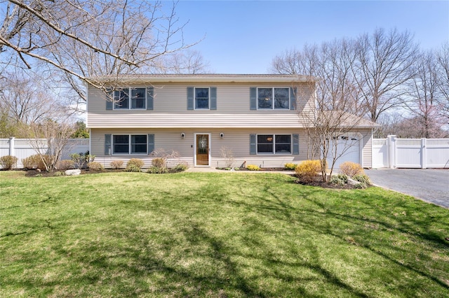 colonial home featuring driveway, a front yard, fence, and a garage