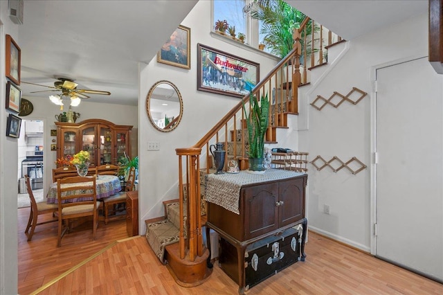 stairway with baseboards, wood finished floors, and a ceiling fan