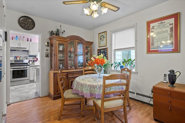 dining space featuring a baseboard radiator, light wood-style floors, and a ceiling fan