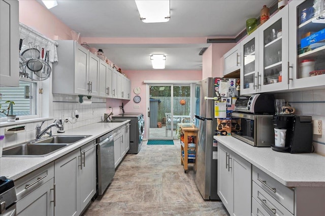 kitchen with backsplash, independent washer and dryer, a sink, and stainless steel appliances