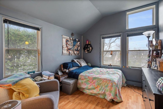 bedroom with lofted ceiling and light wood-style floors