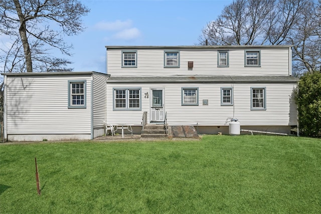 rear view of house featuring entry steps and a lawn