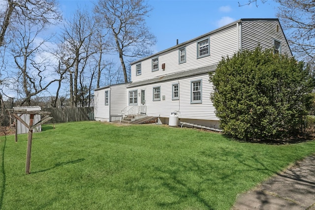 back of property with a yard, an outdoor structure, fence, and a storage unit