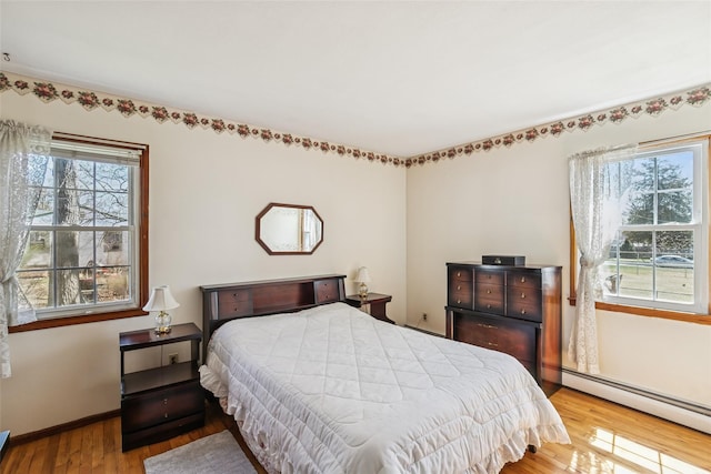 bedroom featuring baseboards, a baseboard heating unit, and wood finished floors