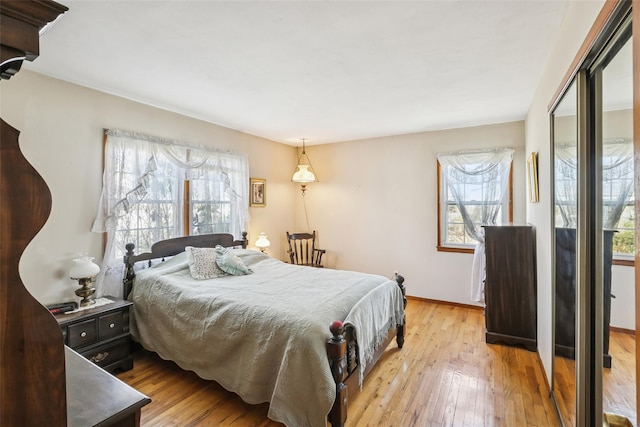 bedroom with wood-type flooring, multiple windows, and baseboards