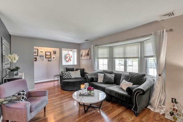 living area with visible vents, a baseboard radiator, wood finished floors, and a healthy amount of sunlight