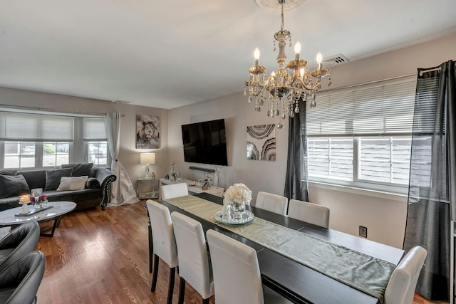 dining space with a chandelier, wood finished floors, and visible vents