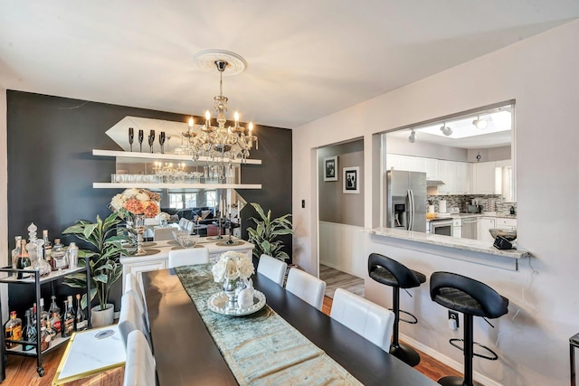 dining area featuring light wood-style flooring and an inviting chandelier