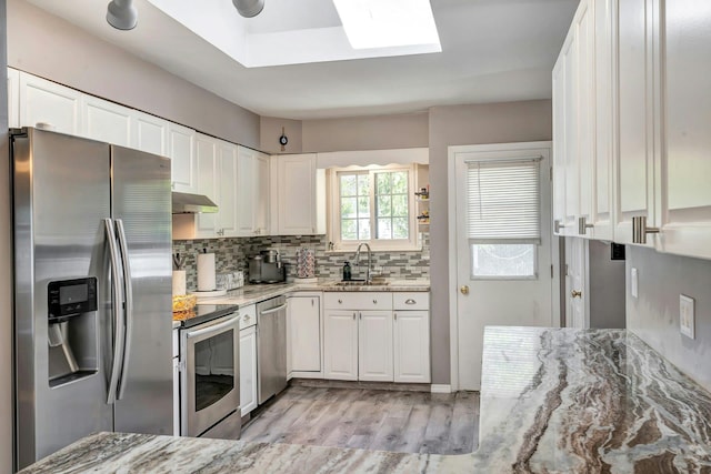 kitchen with white cabinets, light stone countertops, a sink, and appliances with stainless steel finishes