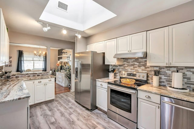 kitchen with white cabinets, under cabinet range hood, a notable chandelier, and appliances with stainless steel finishes