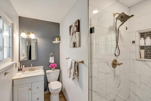 full bath with toilet, a tile shower, and vanity