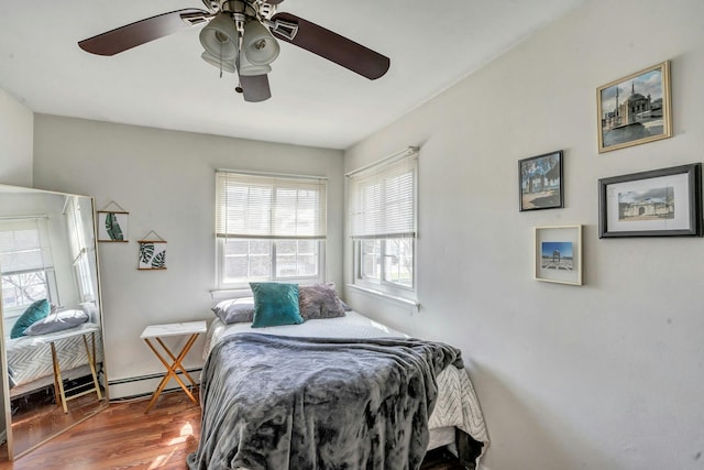 bedroom featuring ceiling fan, a baseboard heating unit, and wood finished floors