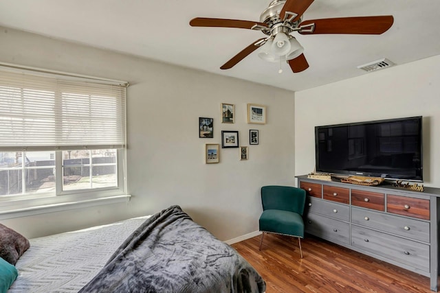 bedroom featuring wood finished floors, baseboards, a ceiling fan, and visible vents