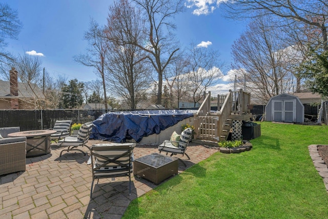 view of yard with a fire pit, a patio area, fence, an outdoor structure, and a storage unit