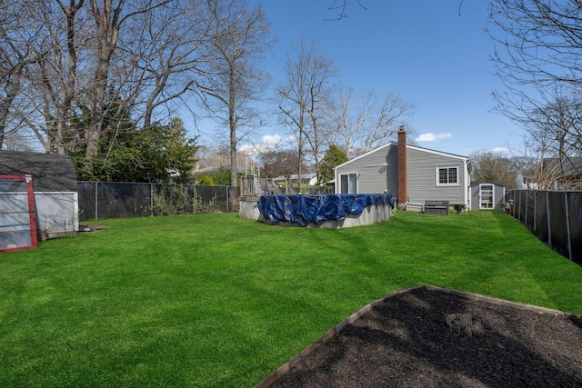 view of yard with a fenced backyard, a fenced in pool, a shed, and an outdoor structure