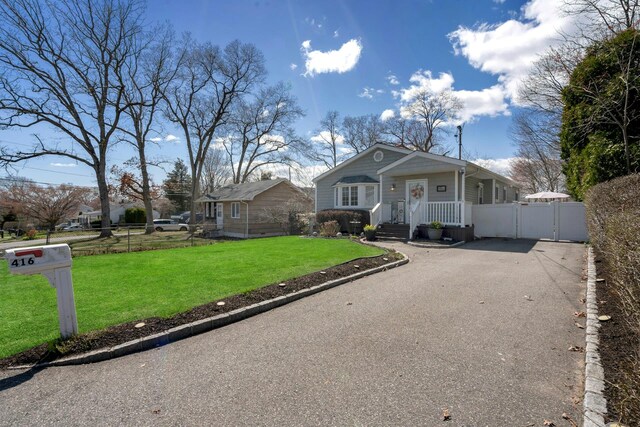 bungalow-style home featuring a front lawn, fence, a gate, and driveway