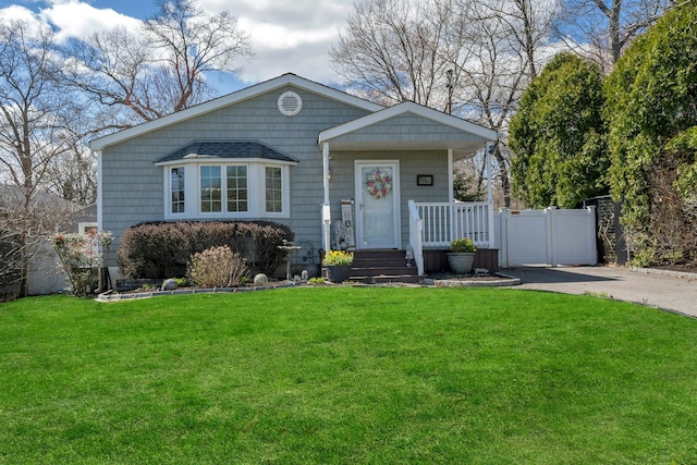 view of front of house featuring fence, driveway, a front lawn, a gate, and covered porch