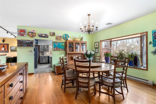 dining area with a baseboard radiator, a chandelier, light wood-type flooring, and rail lighting