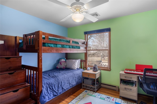 bedroom with baseboard heating, wood finished floors, and a ceiling fan