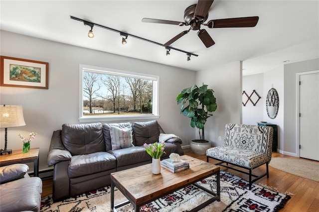 living area featuring track lighting, a ceiling fan, wood finished floors, and baseboards