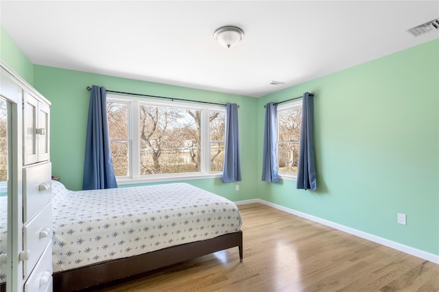 bedroom featuring multiple windows, wood finished floors, and baseboards